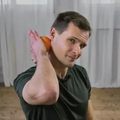 Mann mit Orange am Nacken, zeigt, wie man das Nacken einrenken selber machen kann.
