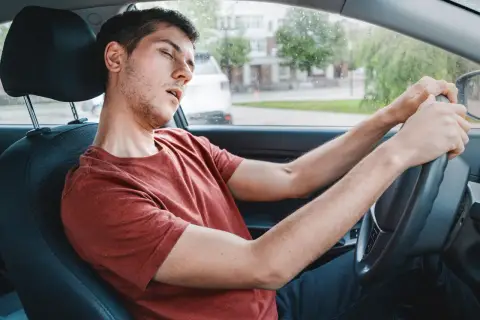 Ein Mann im Auto schläft fast ein, ein gefährlicher sekundenschlaf auf der arbeit.