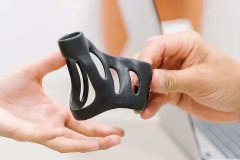 Schwarze Schiene zur Behandlung von Schnappfingern wird von Händen gehalten.