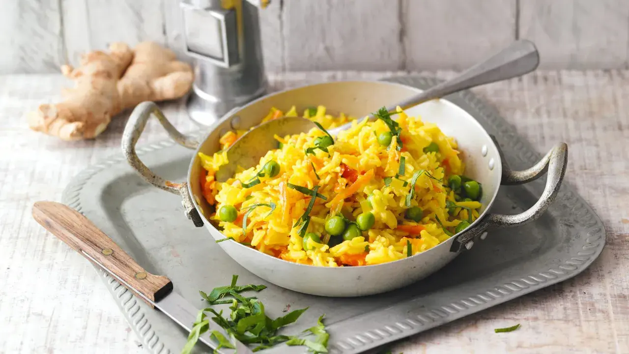 Gelber Reis mit Erbsen und Karotten, ein leckeres Gericht, das an Kurkuma gegen Gelenkschmerzen Rezepte erinnert.
